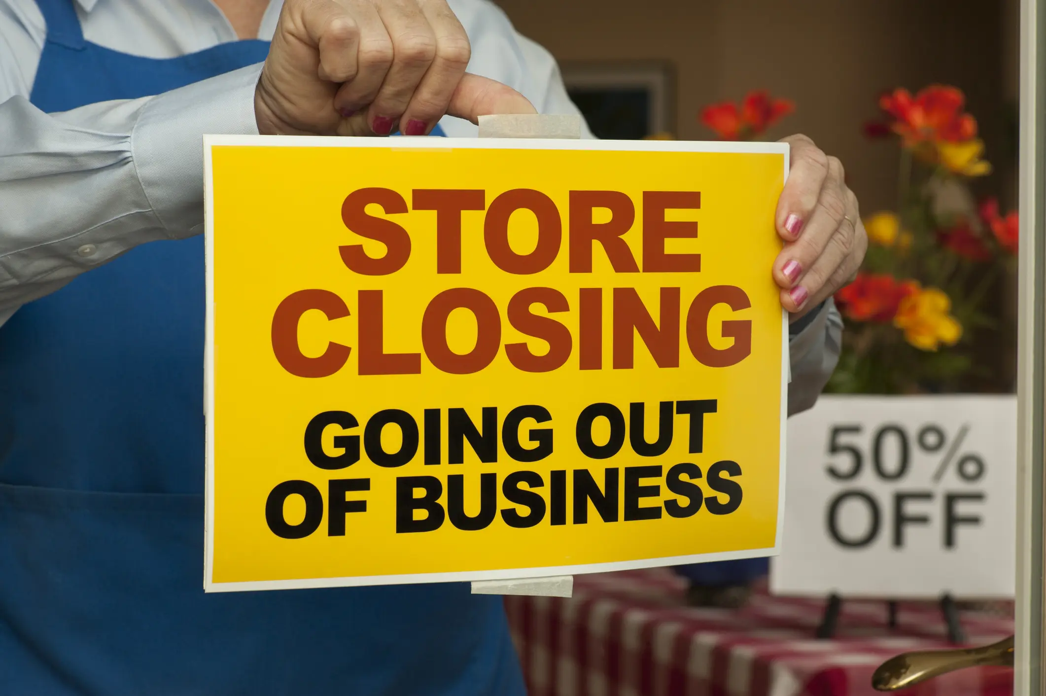 person sticking store closing sign on their store front door