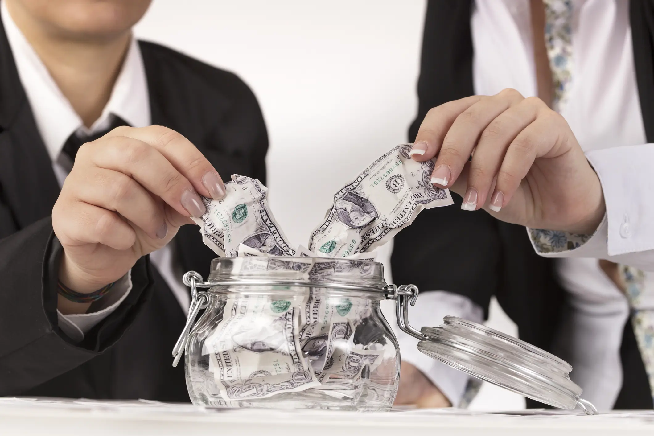 business couple placing their money in a glass jar